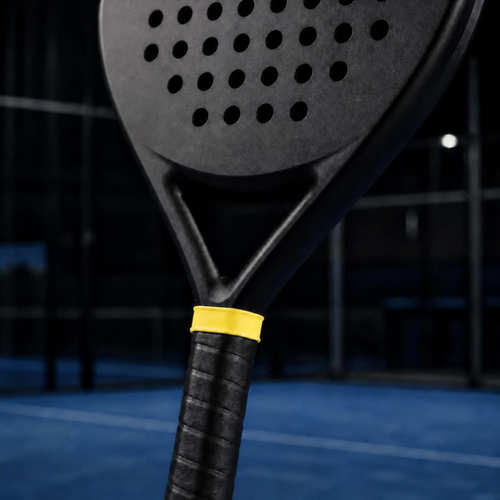 Anneau de manche silicone jaune en haut du manche d'une raquette de padel, maintenant le surgrip (mise en scène générée par IA)