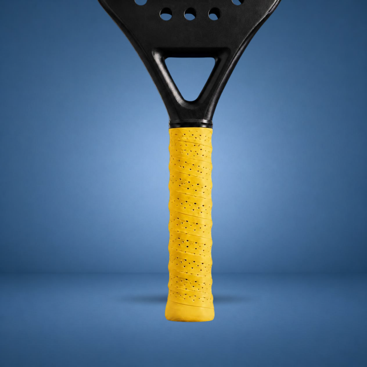 Surgrip perforé jaune sur un manche de raquette de padel, visuel studio sur fond bleu terrain (généré par IA)