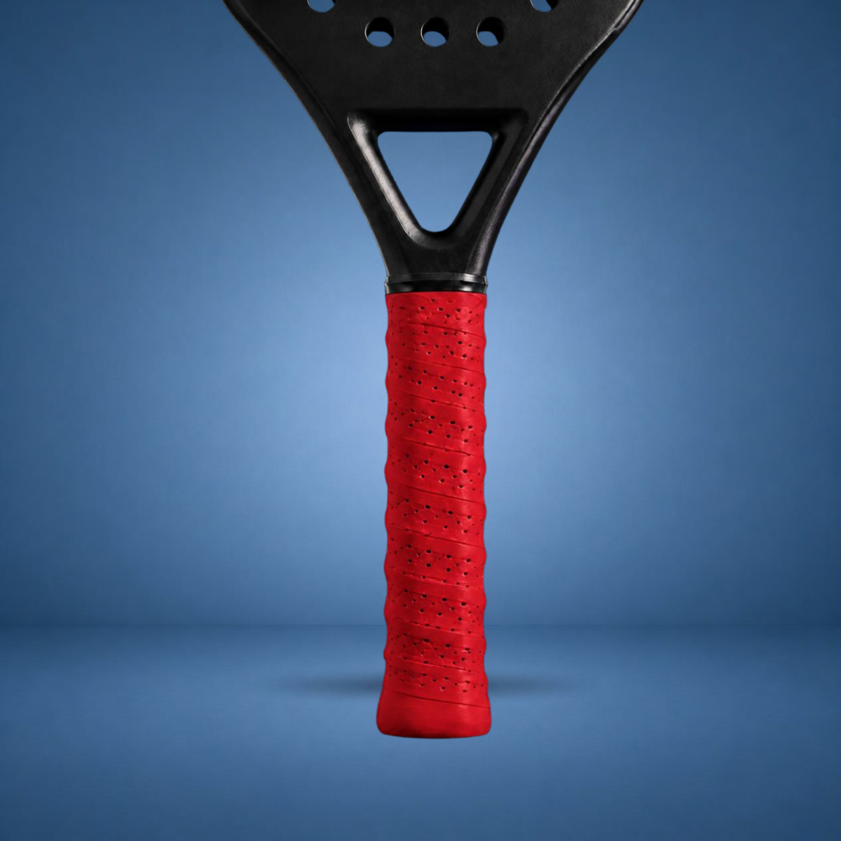 Surgrip perforé rouge sur un manche de raquette de padel, visuel studio sur fond bleu terrain (généré par IA)