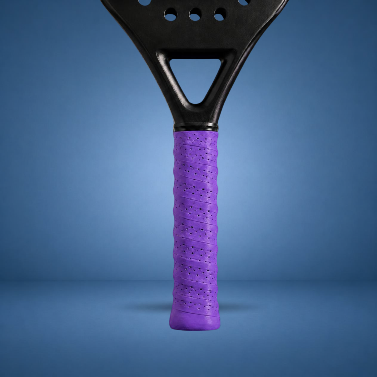 Surgrip perforé violet sur un manche de raquette de padel, visuel studio sur fond bleu terrain (généré par IA)
